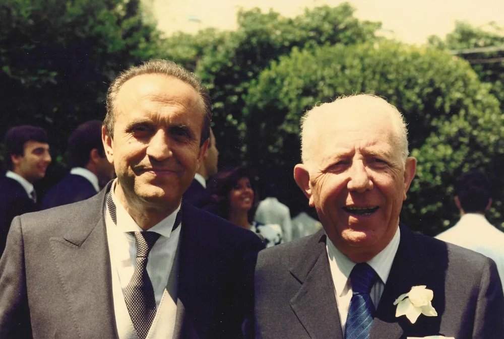 Sorridente, all’aperto, accanto a un altro uomo politico